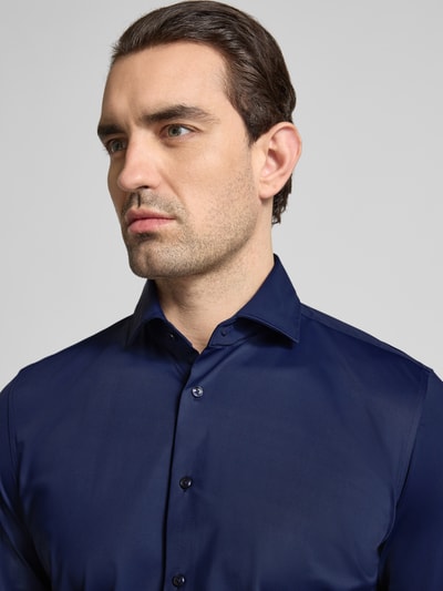 Männermodel trägt Slim Fit Business-Hemd mit Haifischkragen von SEIDENSTICKER in dunkelblau, Material-Mix mit stretch, Nahaufnahme Oberkörper.