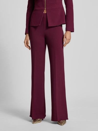 Frauenmodel trägt Flared Fit Stoffhose mit Bügelfalten von Rinascimento in Dunkelrot, glatte Textur, elastischer Bund, Nahaufnahme Oberkörper. Damen Stoffhose aus Material-Mix mit Stretch-Anteil, Bundweite S: 38 cm, Innenbeinlänge S: 85 cm.