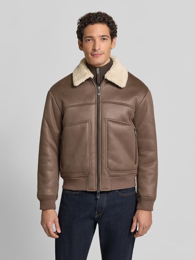 Męski model ma na sobie bluzon w Materiał skóropodobny, krój regular fit, wykładany kołnierz z futerka, zamek błyskawiczny dwustronny, Blouson in Leder-Optik mit Zweiwege-Reißverschluss od Armani Exchange, brązowe odcienie, Ganzkörperansicht von vorne.