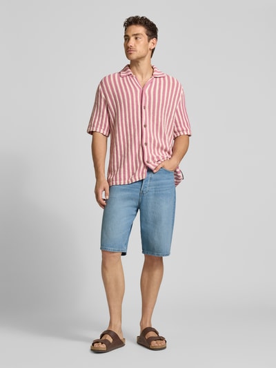Männermodel trägt Loose Fit Jeansshorts aus Lyocell-Baumwoll-Mix Modell 'BAGGY HEMP BLEND' von Armedangels, 5-Pocket-Design in Denim-Optik, hellblaue Farbe, Label Patch und Gürtelschlaufen sichtbar, Ganzkörperansicht von vorne.