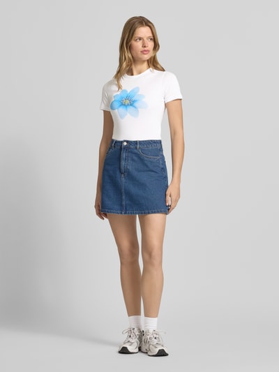 Frauenmodel trägt Damen T-Shirt mit blauem Motiv-Print Modell 'GIGI' von JJXX aus Baumwoll-Mix mit Stretch-Anteil, gerader Schnitt, Rundhalsausschnitt, Rückenlänge bei Größe S 49 cm, Farben Weiß und Blau, glatte Textur, Ganzkörperansicht von vorne.