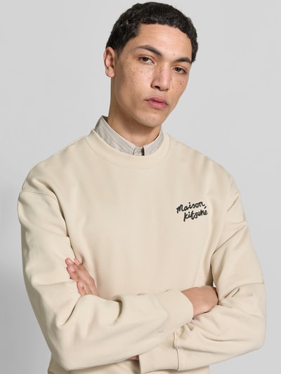 Männermodel trägt Sweatshirt aus Baumwoll-Mix von MAISON KITSUNÉ in Beige mit Label-Stitching, lockerer Passform, Nahaufnahme Oberkörper.