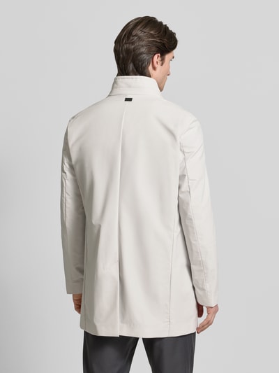Männermodel trägt Regular Fit Mantel mit Stehkragen Modell 'FYNN' von Strellson, effen beige twill, lange mouwen, Ganzkörperansicht Rückansicht.