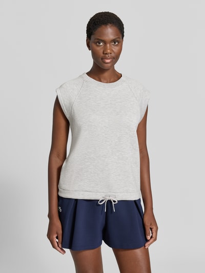 Modelka nosi Relaxed Fit Sweatshirt aus Viskose-Mix Modell 'Salome' von VARLEY, mieszanka wiskozy, krój relaxed fit, okrągły dekolt, bez rękawów, pas z tunelem, jasnoszara bluza i granatowe szorty, gładkie tekstury, widok na cały przód sylwetki.