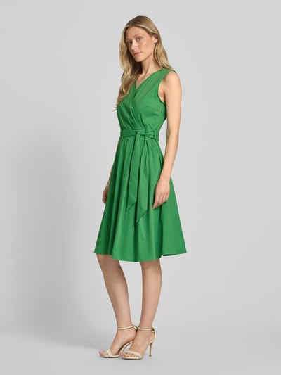 Vrouwenmodel draagt 'Kleid mit V-Ausschnitt in Wickel-Optik' van More & More in groen, katoenmix, getailleerde pasvorm, mouwloos design, tailleband, zijaanzicht, volledige lichaamsopname