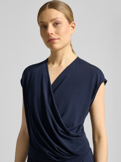 Vrouwenmodel draagt Jumpsuit in Wickel-Optik mit V-Ausschnitt van ROBE LÉGÈRE in donkerblauw materiaalmix met stretch, regular fit, wikkellook, V-hals, Nahaufnahme bovenlichaam.
