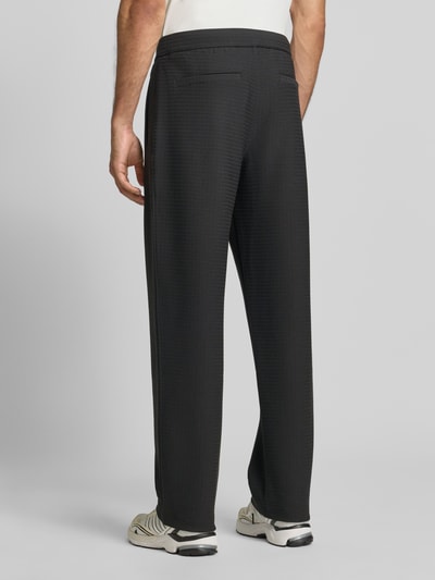 Männermodel trägt Wide Fit Sweatpants mit Lyocell-Anteil von Emporio Armani in Schwarz, elastischer Bund, strukturierte Oberfläche, Ganzkörperansicht Rückansicht.