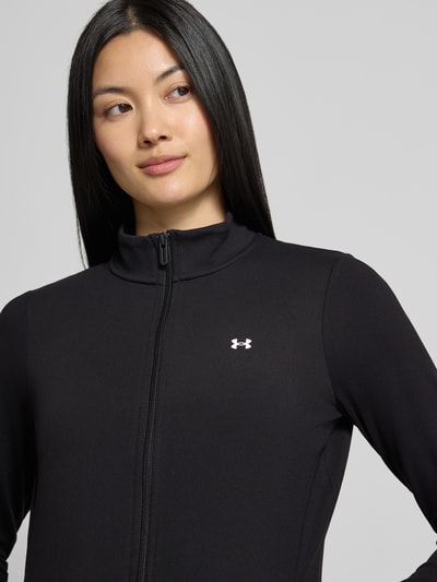 Frauenmodel trägt schwarze Slim Fit Trainingsjacke mit Logo-Print von Under Armour, glatte Textur, Nahaufnahme Oberkörper, Damen Trainingsjacke von Under Armour.