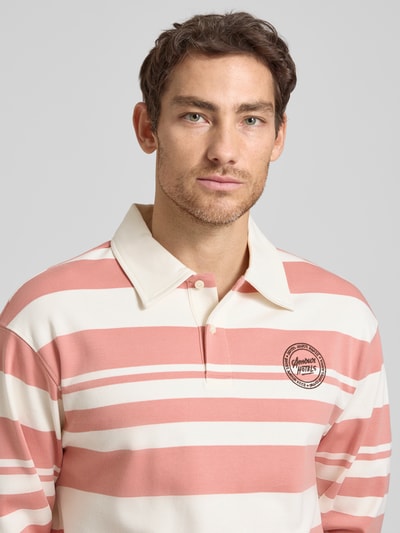 Męski model prezentuje koszulkę polo Relaxed Fit Poloshirt aus reiner Bio-Baumwolle Modell 'JACK' von SELECTED HOMME, efekt: wzór na całej powierzchni, kołnierzyk polo, zapięcie na 2 guziki, długi rękaw, wyhaftowane logo, dzianina dresowa, bawełna ekologiczna, zbliżenie na górną część ciała.
