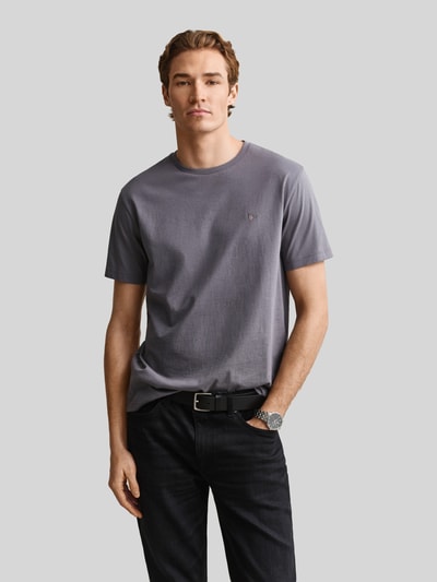 Männermodel trägt Regular Fit T-Shirt aus reiner Baumwolle von GANT in Grau, schlichtes Design, glatte Textur, Ganzkörperansicht von vorne. Herren T-Shirt.