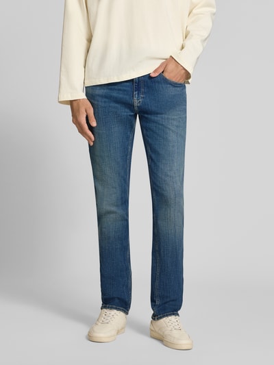 Männermodel trägt Slim Fit Jeans aus Baumwoll-Mix Modell 'SCANTON SLIM' von Tommy Jeans in Denim-Optik mit Label Patch, Ganzkörperansicht von vorne.
