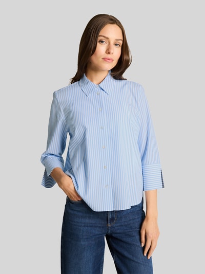 Frauenmodel trägt Regular Fit Hemdbluse aus Lyocell-Baumwoll-Mix von Tom Tailor, Optik: Unifarben, Passform: Regular-Fit, Hemdkragen, ohne Muster, einreihige Knopfleiste, Kimonoärmel, Materialverarbeitung: Popeline, Farben in Hellblau mit feiner Streifen-Optik, glatte Textur, Ganzkörperansicht von vorne.