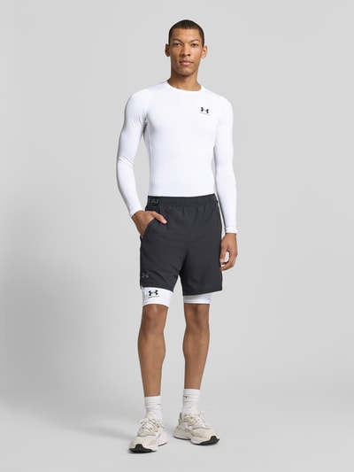 Männermodel trägt Shorts mit elastischem Logo-Bund von Under Armour aus Material-Mix mit Stretch-Anteil, Label-Print, Ganzkörperansicht von vorne.