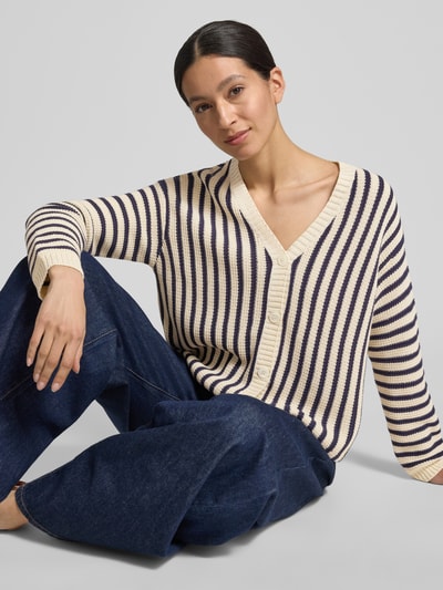Vrouwenmodel draagt Regular Fit gebreid jack uit puur katoen model 'NICCHIA' van Weekend Max Mara met all-over motief, V-hals, lange mouw, knoopsluiting, knitwear structuur, kleuren beige en donkerblauw, volledig vooraanzicht van bovenlichaam.