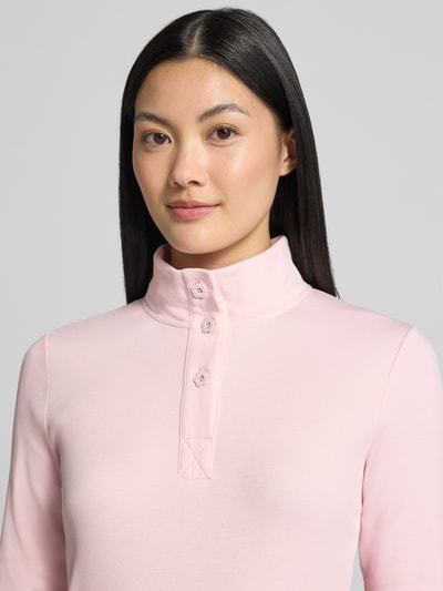 Kobiece modelka nosi bluzkę z długim rękawem Slim Fit Longsleeve aus Baumwoll-Mix von Marc Cain w kolorze jasnoróżowym, stójka, listwa guzikowa, mieszanka bawełny, długość tyłu w rozmiarze 36: 55 cm, zbliżenie na górną część ciała.