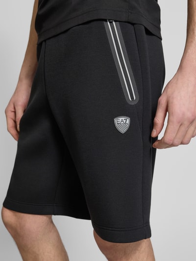 Männermodel trägt Shorts mit elastischem Bund von EA7 Emporio Armani, Regular Fit, Material-Mix in Schwarz, Nahaufnahme Oberschenkel.