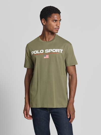 Męski model trägt Regular Fit T-Shirt aus reiner Baumwolle von Polo Ralph Lauren w kolorze khaki z białym nadrukiem, Ganzkörperansicht von vorne, Męski t-shirt Polo Ralph Lauren