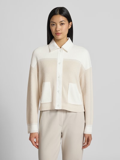 Frauenmodel trägt Regular Fit Jacke in Strick-Optik von Marc Cain aus Baumwoll-Mix in Beige und Weiß, Umlegekragen, aufgesetzte Taschen, durchgehende Knopfleiste, Ganzkörperansicht von vorne.