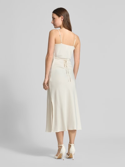Frauenmodel trägt Slim Fit Midikleid mit abnehmbarem Stoffband Modell 'Thea' von YAS, cremefarben, glatter Stoff, Ganzkörperansicht Rückansicht. Elastischer Material-Mix, verstellbare Spaghettiträger, Midilänge.
