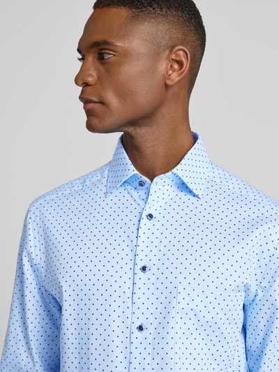 Männermodel trägt Regular Fit Businesshemd aus reiner Baumwolle mit Kentkragen von OLYMP, hellblau mit kleinen Punkten, Nahaufnahme Oberkörper.