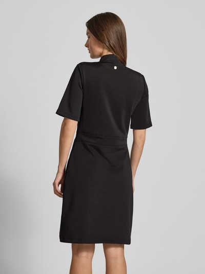 Frauenmodel trägt Kleid mit Stehkragen und Knopfleiste Modell 'Tibra' von JOOP! aus schwarzem Material-Mix mit Baumwoll-Anteil, A-Linie, Mini, 1/2-Arm, Rückansicht Ganzkörperansicht.