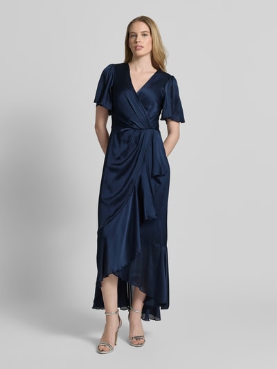 Frauenmodel trägt Cocktailkleid in Wickel-Optik mit V-Ausschnitt von Lipsy in Dunkelblau, Satin, tailliert, Maxikleid, Volantsaum, blickdichtes Unterkleid, Ganzkörperansicht von vorne.