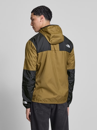 Mannenmodel draagt Regular Fit Jacke mit Logo-Print Modell 'Mountain' van The North Face in olijfgroen en zwart met capuchon, steekzakken met ritssluiting, elastische boorden; ruglengte maat M 72 cm, schouderbreedte 48 cm, borstwijdte 53 cm, mouwlengte 70 cm; Ganzkörperansicht Rückansicht.