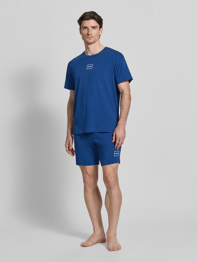 Männermodel trägt Regular Fit Sweatshorts aus Baumwoll-Mix Modell 'LAZE SHORTS CW' von HUGO, Optik: Unifarben, Applikation: Label-Print, Bundabschluss: Elastisch, Material: Baumwoll-Mix, Ganzkörperansicht von vorne.