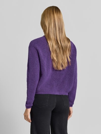 Frauenmodel trägt Relaxed Fit Strickjacke aus Woll-Mix mit Leinen-Anteil von American Vintage in Lila, gerippte Bündchen, Rückenansicht, Ganzkörperansicht Rückansicht.