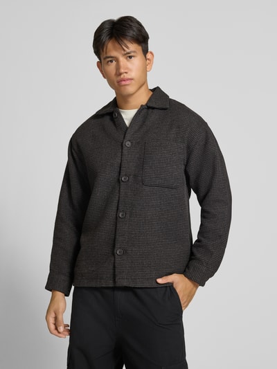 Männermodel trägt Regular Fit Hemdjacke mit Brusttasche Modell 'SOHO OLLIE' von JACK & JONES in dunklem Grau, Ganzkörperansicht von vorne. Rückenlänge 71 cm, Schulterbreite 41 cm, Ärmellänge 65 cm.