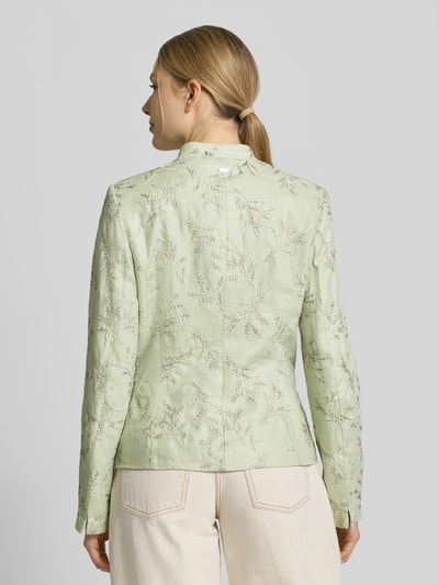 Modelka kobieta nosi Slim Fit Blazer mit Stitchings und Stehkragen od WHITE LABEL, jasnozielony kolor, faktura z przeszyciami, krój slim fit, stebnowania, stójka, kieszenie, długość tyłu w rozmiarze 36: 59 cm, szerokość w rozmiarze 36: 47 cm, długość rękawa w rozmiarze 36: 65 cm, całkowity widok z tyłu.