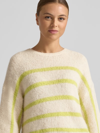 Frauenmodel trägt Strickpullover mit 3/4-Ärmel von Rich & Royal, Alpaka-Mix, lockerer Schnitt, creme mit gelben Streifen, Nahaufnahme Oberkörper.