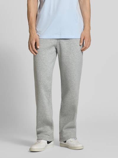 Männermodel trägt Sweatpants mit Logo-Stitching und Eingrifftaschen von Nike aus Baumwoll-Mix in Grau, Loose-Fit, Ganzkörperansicht von vorne.