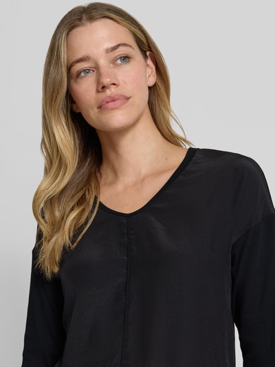 Frauenmodel trägt T-Shirt mit Ärmelaufschlag und Rundhalsausschnitt von Marc Cain aus Baumwoll-Mix mit Stretch-Anteil, Label-Detail, Straight Fit, schwarze Farbgebung, glatte Textur, Nahaufnahme Oberkörper. Rückenlänge bei Größe 36: 62 cm.
