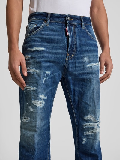 Männermodel trägt Slim Fit Jeans aus reiner Baumwolle von Dsquared2 im Destroyed-Look, 5-Pocket-Design, Nahaufnahme Oberkörper. Innenbeinlänge 45 cm, Bundweite 80 cm, Knopf- und Reißverschluss, blaue Used-Optik.