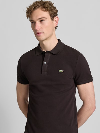 Männermodel trägt Slim Fit Poloshirt aus reiner Baumwolle von Lacoste, unifarben, Logo-Stitching, Piqué-Struktur, Nahaufnahme Oberkörper.