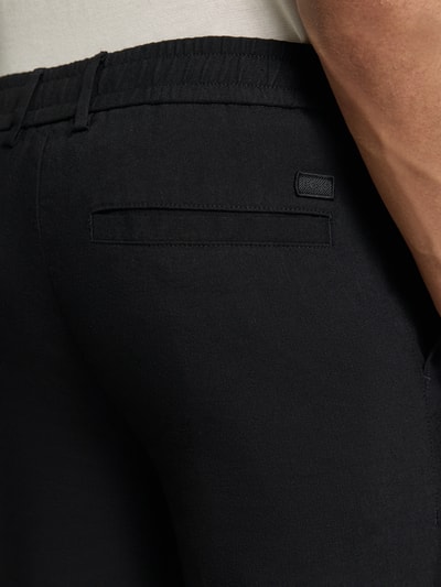 Männermodel trägt Modern Fit Straight Leg Hose aus Leinen-Mix Modell 'KANE1' von BOSS in Schwarz, Leinenstruktur, Nahaufnahme Rückansicht