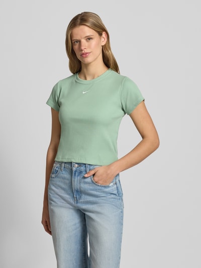 Frauenmodel trägt Cropped T-Shirt in Ripp-Optik mit Logo von Nike aus Baumwoll-Elasthan-Mix, Rundhalsausschnitt, hellgrün, Ganzkörperansicht von vorne. Rückenlänge bei Größe S: 50 cm.
