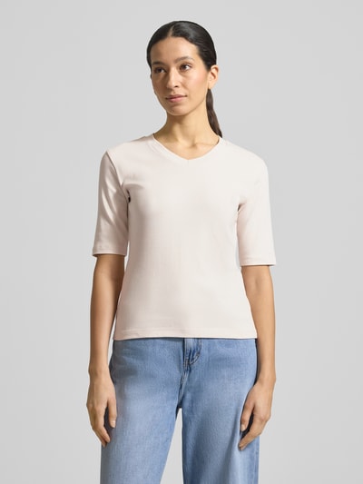 Kobiece modelka nosi T-shirt mit V-Ausschnitt od Christian Berg Woman, mieszanka bawełny i elastanu, krój regular fit, dekolt w serek, rękaw o dł. 1/2, długość tyłu w rozmiarze S: 55 cm, jasny kolor, gładka faktura, całopostaciowy widok z przodu.