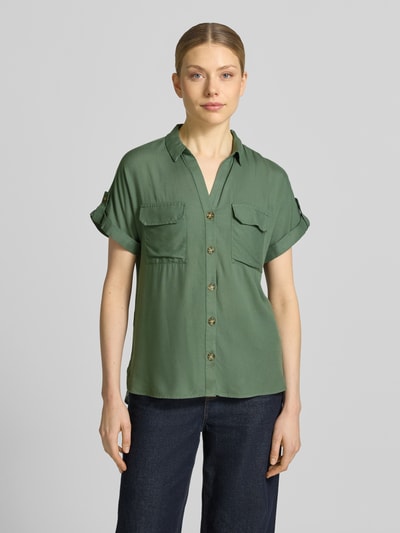 Kobiece modelka nosi Regular Fit Hemdbluse aus reiner Viskose Modell 'BUMPY' od Vero Moda, kolor zielony, gładka struktura, krótkie rękawy, kołnierzyk koszulowy, dwie kieszenie na piersiach, materiał w 100% wiskoza, widok całej sylwetki z przodu.