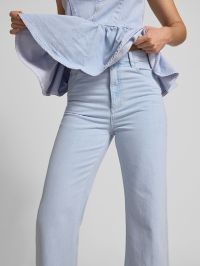 Frauenmodel trägt Straight Fit Jeans mit Logo-Patch von BAUM & PFERDGARTEN, hellblau, Baumwoll-Mix, 5-Pocket-Design, Nahaufnahme Oberkörper.