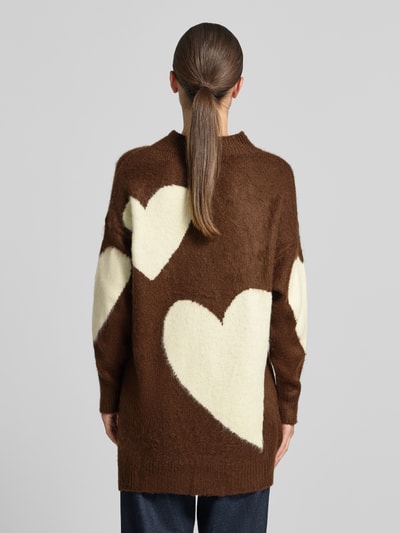 Modelka prezentuje Sweter z dzianiny z mieszanki wełny z alpaki i bawełny od miss goodlife, brązowy z kremowymi sercami, luźny krój, prążkowana stójka, prążkowane wykończenia, Długość tyłu w rozmiarze S: 73 cm, Długość rękawów w rozmiarze S: 47 cm, widok całej sylwetki od tyłu.