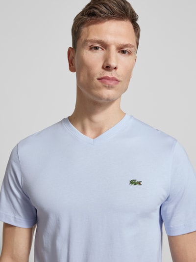 Männermodel trägt Regular Fit T-Shirt aus reiner Baumwolle von Lacoste in Hellblau, V-Ausschnitt, Logo-Stitching, Nahaufnahme Oberkörper