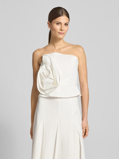 Frauenmodel trägt Slim Fit Top mit floraler Applikation von Jake*s Cocktail in Weiß, Strukturmuster, schulterfreies Design, Nahaufnahme Oberkörper.