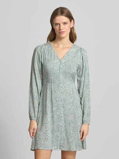 Frauenmodel trägt tailliertes Damen Freizeitkleid aus reiner Viskose Modell 'EVIDA' von Only, Optik: Allover-Muster, Mini-Länge, V-Ausschnitt, Knopfleiste, Langarm mit Ballonärmel und Knopf mit Öse, glatte strukturierte Oberfläche, Ganzkörperansicht von vorne.