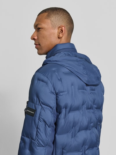 Männermodel trägt Regular Fit Bomberjacke mit reflektierenden Details von Tom Tailor, blaue Steppoptik, Detailaufnahme Rückansicht. Herren Bomberjacke / Blouson.