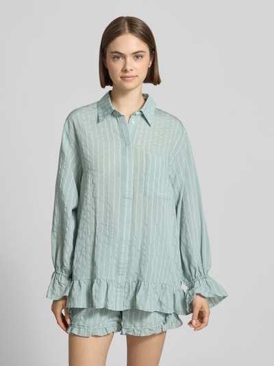 Frauenmodel trägt Bluse aus Viskose-Mix mit Brusttasche Modell 'Selina' von OH APRIL in hellem Mint, Rüschenärmel und Rüschensaum, Hemdblusenkragen, verdeckte Knopfleiste, Straight Fit, Rückenlänge bei Größe S 73 cm, Ärmellänge 61 cm, Ganzkörperansicht von vorne.