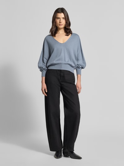 Kobiece modelka nosi niebieski Strickpullover aus Baumwoll-Kaschmir-Mix Modell 'RISORY' od Drykorn, krój relaxed fit, z dekoltem w serek, materiał gładki; widok całej sylwetki z przodu.