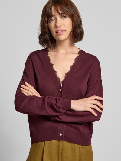 Kobiece model prezentuje kardigan mit V-Ausschnitt und Spitzenbesatz von Jake*s Casual, Mieszanka materiałów z domieszką lnu, krój regular fit, dekolt w serek, obszycie koronką, listwa guzikowa, długość tyłu w rozmiarze S: 55 cm, długość rękawów w rozmiarze S: 49 cm, bordowy i oliwkowy kolor, wyraźna faktura materiału, widok na górną część ciała z przodu