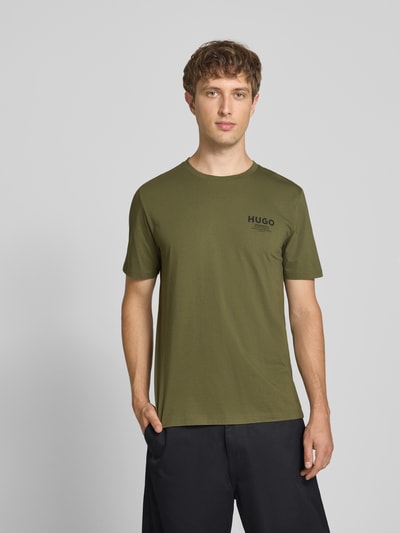 Männermodel trägt Regular Fit T-Shirt aus reiner Baumwolle Modell 'NESPTEE' van HUGO Blue, olijfgroen, Ganzkörperansicht von vorne